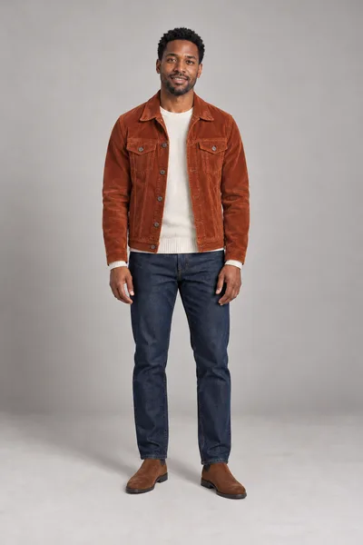Homem de jaqueta de veludo cotelê laranja-ferrugem, suéter de tricô creme, calça jeans escura e botas de camurça marrons, criado a partir de uma descrição escrita — prévia do trocador de roupa com IA