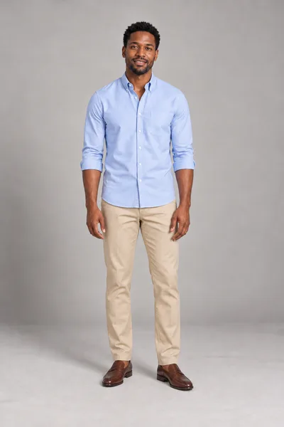 Homem de camisa oxford azul-clara com as mangas dobradas, calça chino bege e mocassins marrons — prévia do trocador de roupa com IA