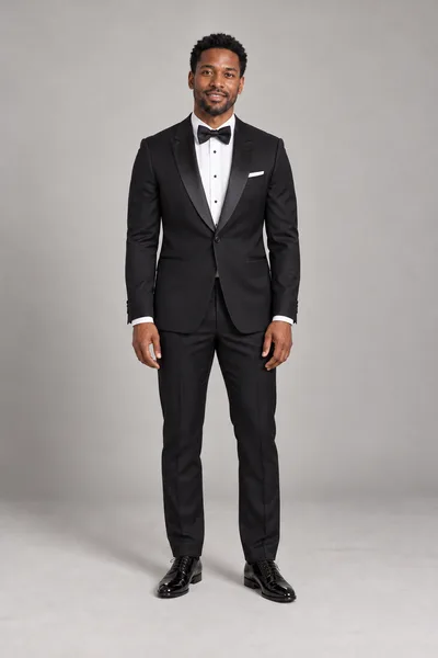 Homem de smoking preto com lapelas de cetim, camisa social branca, gravata-borboleta preta e sapatos de verniz — prévia do trocador de roupa com IA
