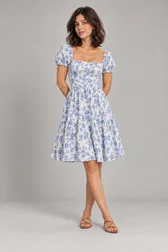 Mulher de vestido floral azul e branco na altura do joelho e sandálias caramelo — prévia do trocador de roupa com IA
